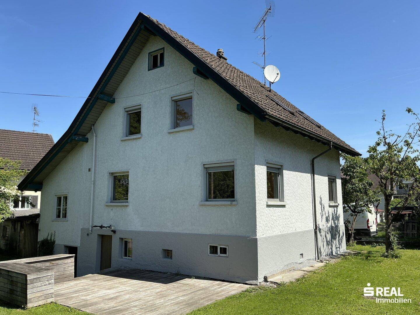 Rückansicht des Hauses mit einer Holzterrasse und Blick auf den gepflegten Garten.