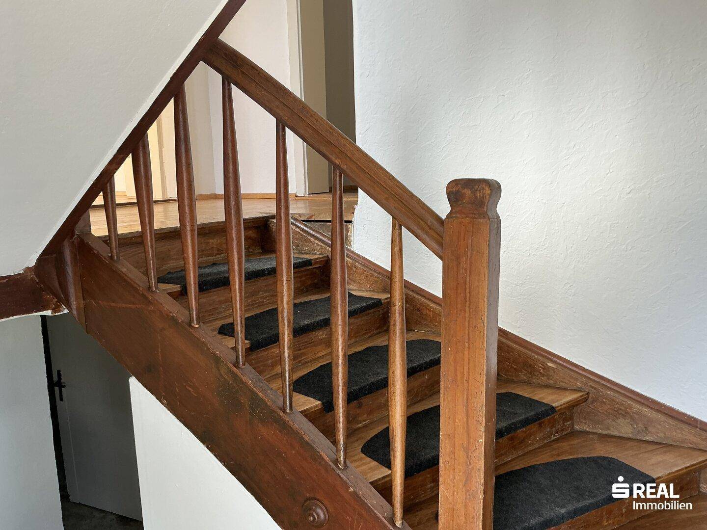 Rustikale Holztreppe mit Teppichstufen, die die verschiedenen Etagen des Hauses verbindet.