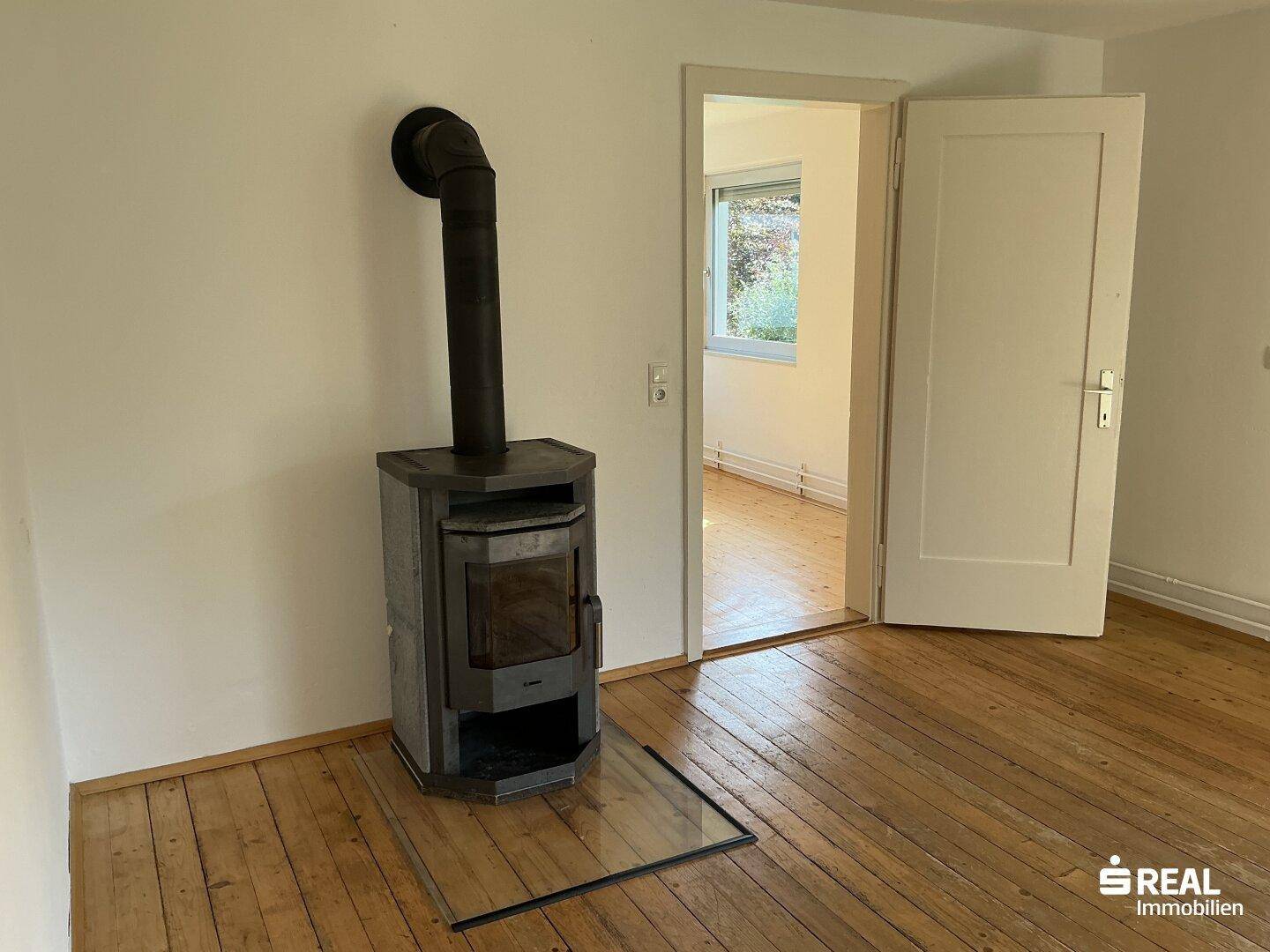 Gemütliches Wohnzimmer mit Holzdielenboden und einem modernen Holzofen für warme Abende.
