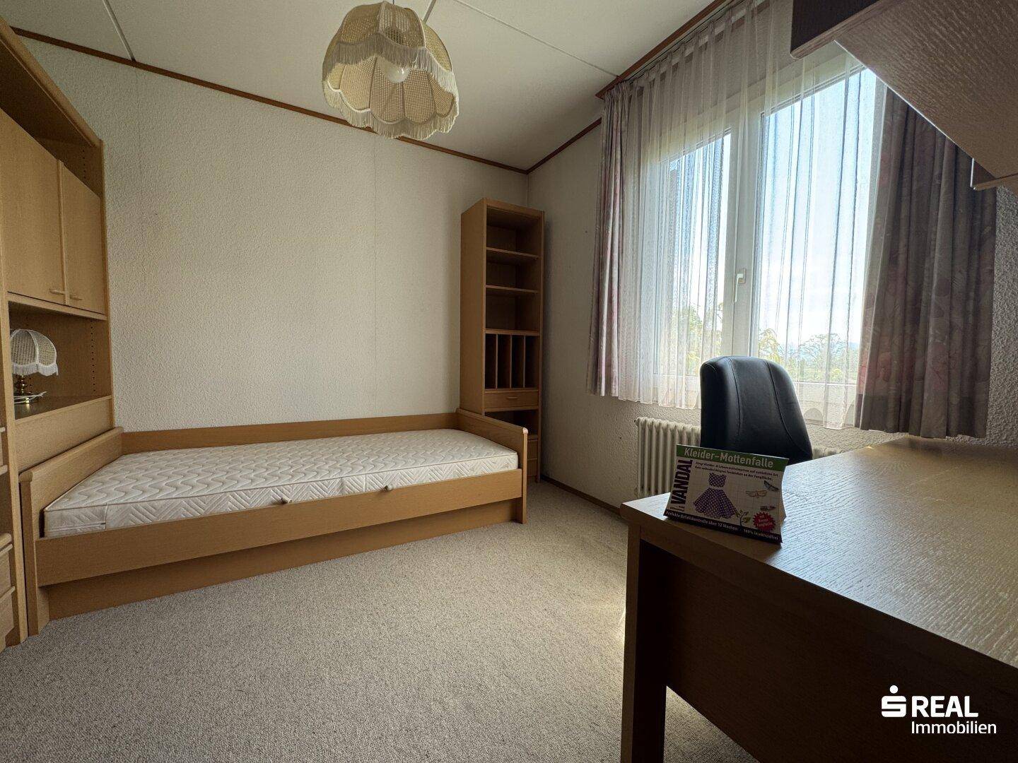 Kinderzimmer mit Teppichboden, Einzelbett und Schreibtisch am Fenster, bietet viel Tageslicht.