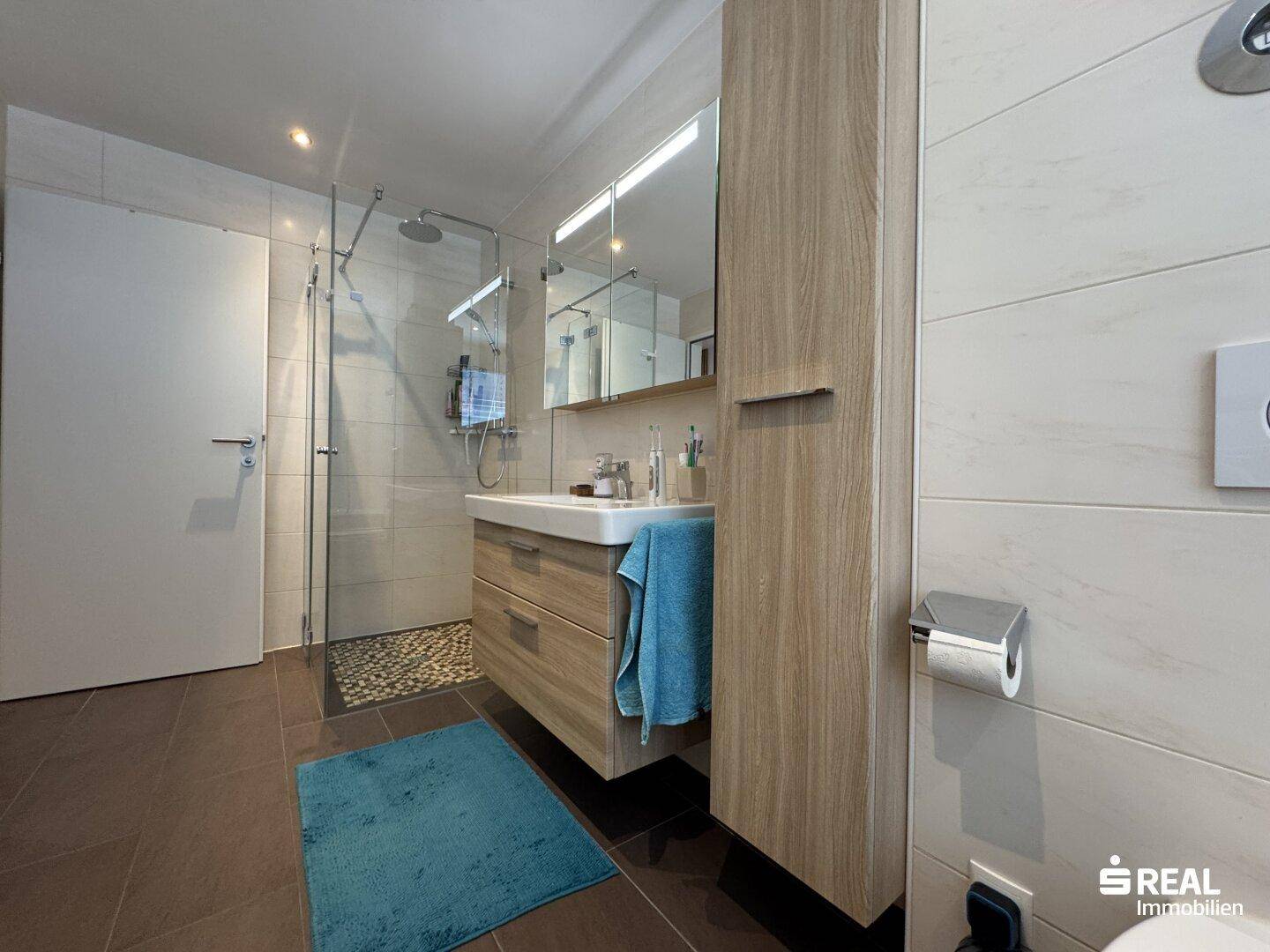 Helles Badezimmer mit begehbarer Dusche, modernem Waschtisch und Spiegelschrank.