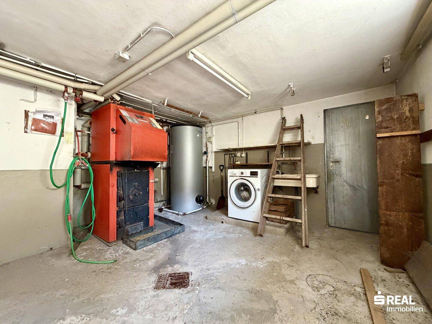 Hauswirtschaftsraum im Keller mit Heizungsanlage, Waschmaschine und Waschbecken.