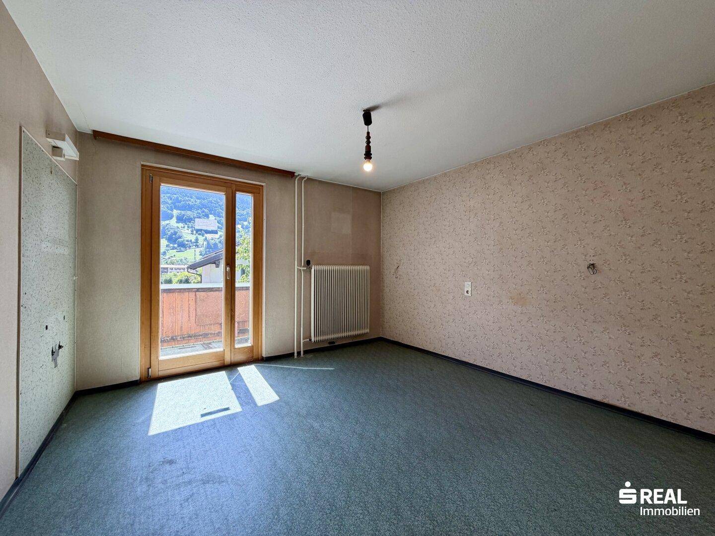 Schlafzimmer mit gemusterter Tapete und Balkonzugang, hell und mit Ausblick.