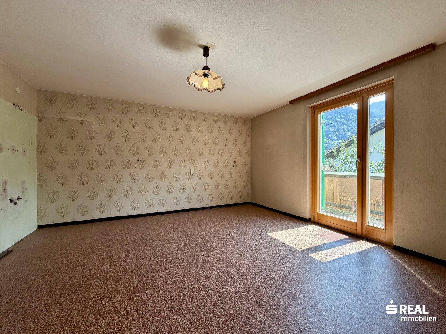 Weiteres Schlafzimmer mit gemusterter Tapete und Zugang zum Balkon, sonnig und hell.