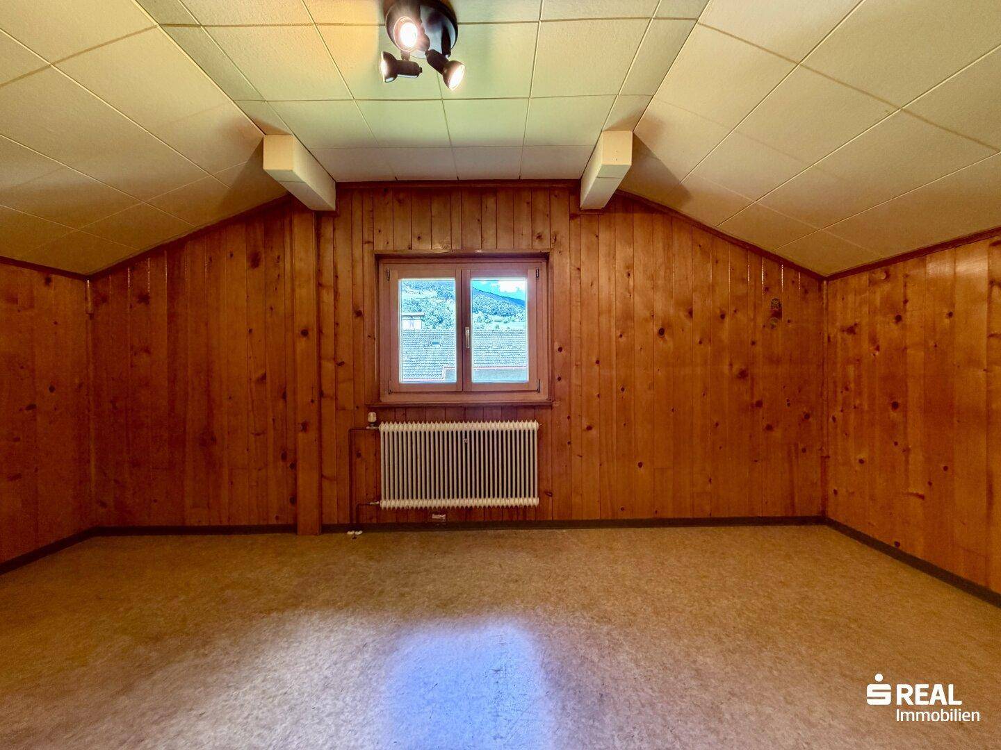 Dachzimmer mit Holzvertäfelung und schrägen Decken, bietet viel Potenzial.