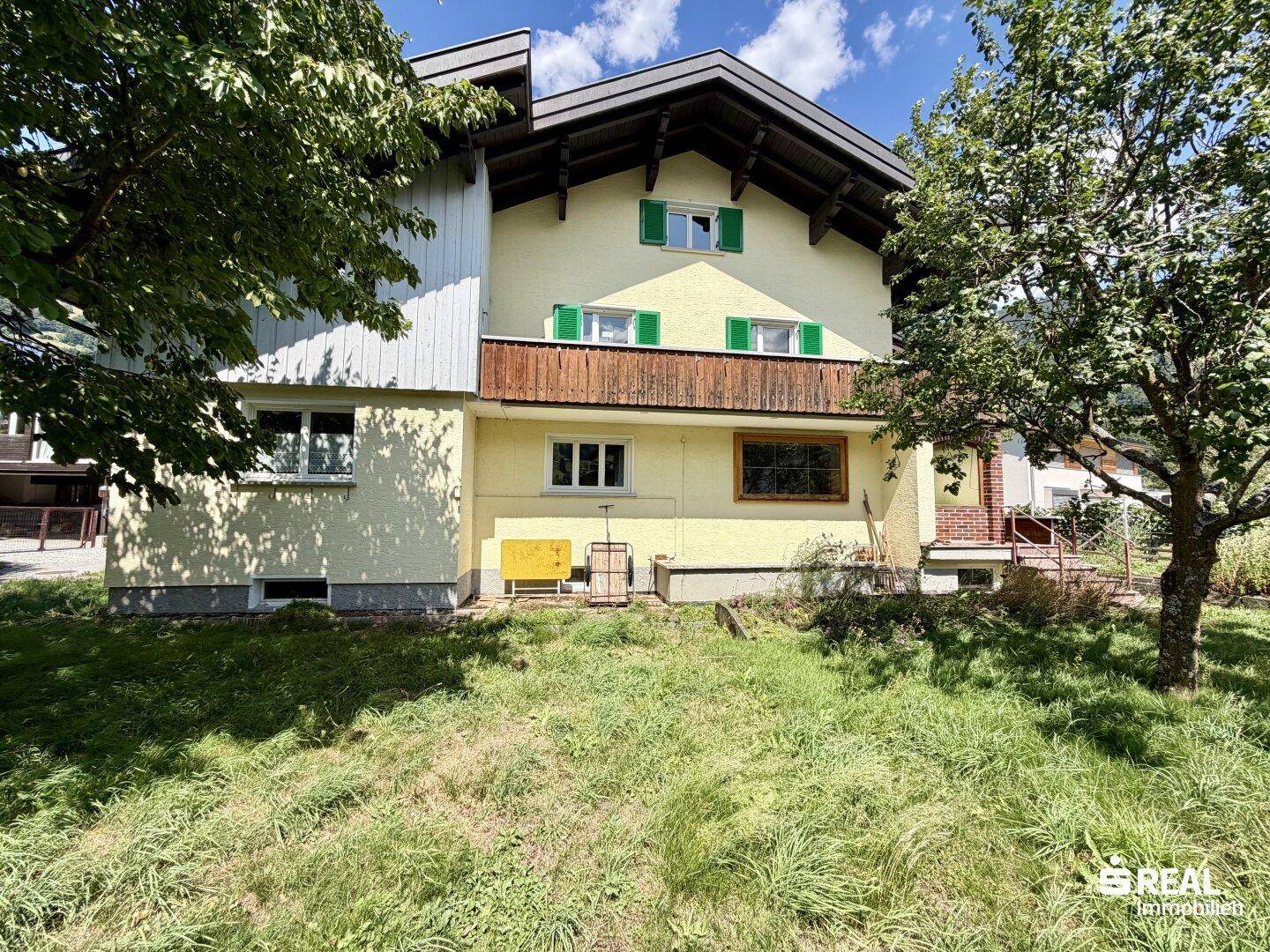 Rückansicht des Hauses mit Balkon und einer kleinen Rasenfläche im Garten.