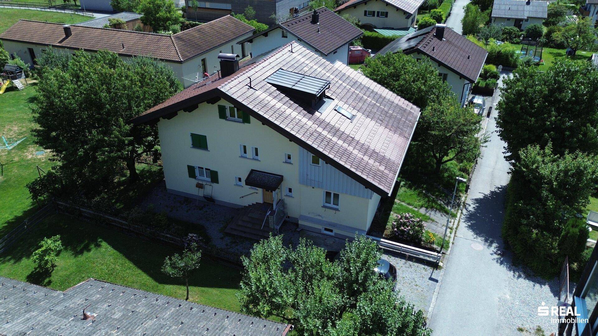 Luftaufnahme eines Einfamilienhauses mit Satteldach und grüner Umgebung.
