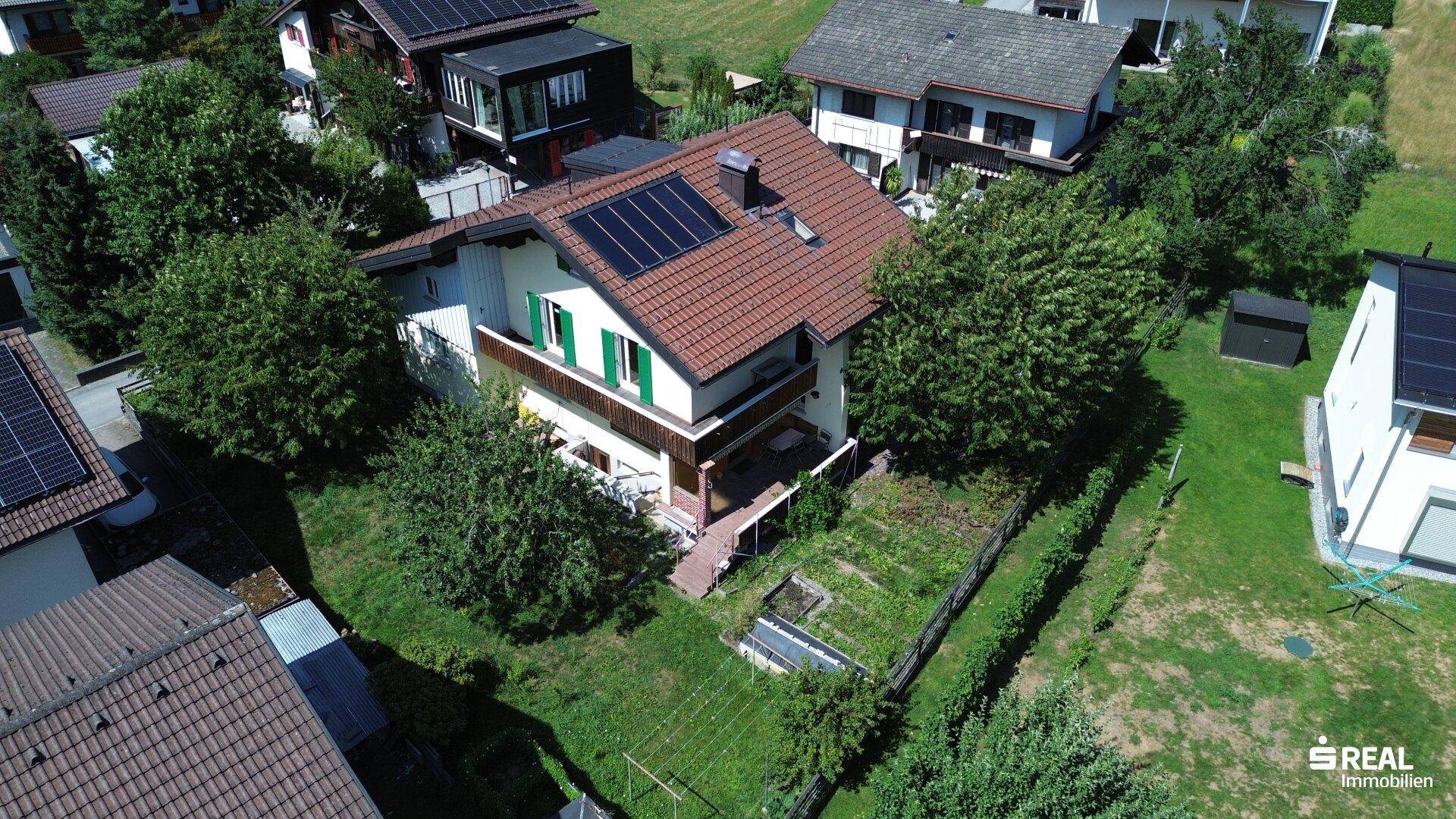 Luftaufnahme des Hauses mit Solaranlage auf dem Dach und umliegender grüner Landschaft.
