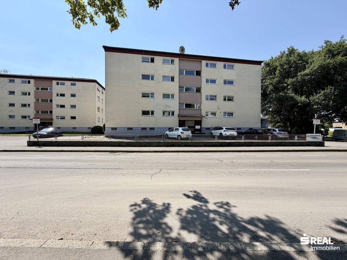 Ansicht des Mehrfamilienhauses von der Straße aus mit weiteren Gebäuden im Hintergrund.