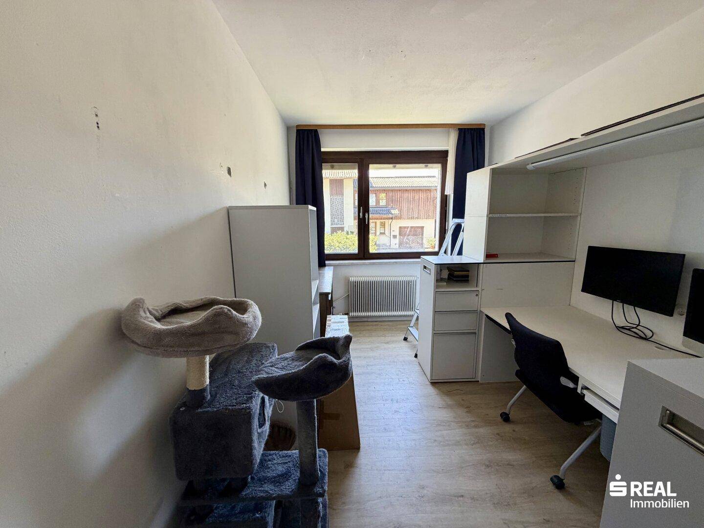 Arbeitszimmer mit Schreibtisch, Regalen und einem Katzenbaum, ideal für Home-Office.