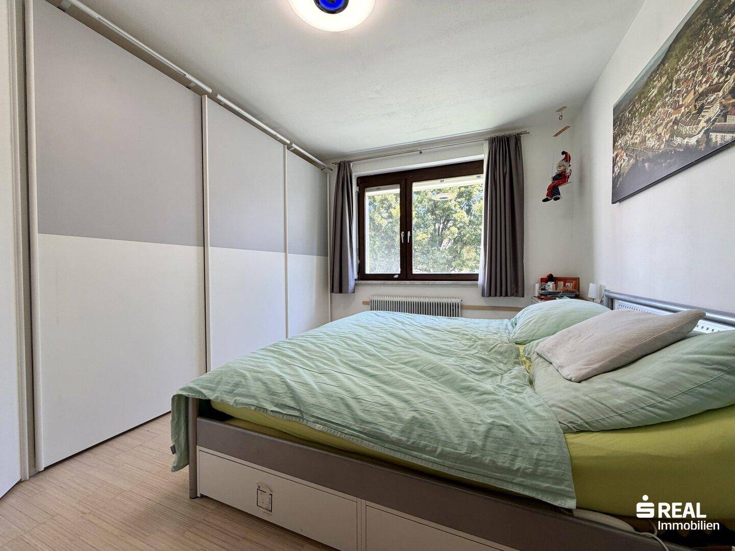 Schlafzimmer mit Doppelbett, Einbauschränken und Fenster mit Blick ins Grüne.