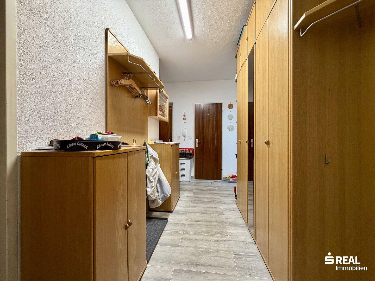 Flur mit praktischen Holz-Einbauschränken und Garderobe.