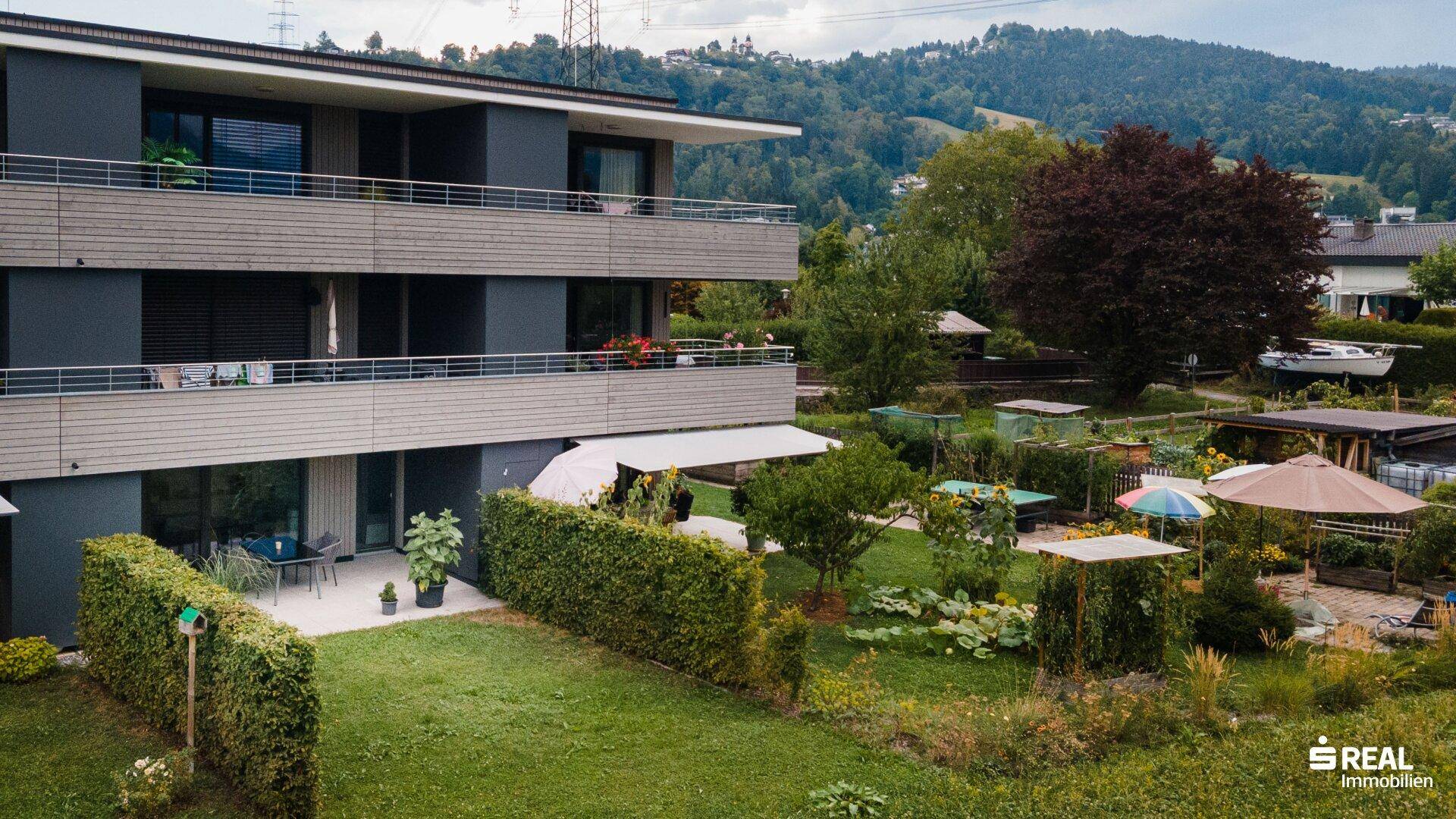 Mehrfamilienhaus mit Balkonen und gepflegtem Gartenbereich im Grünen.
