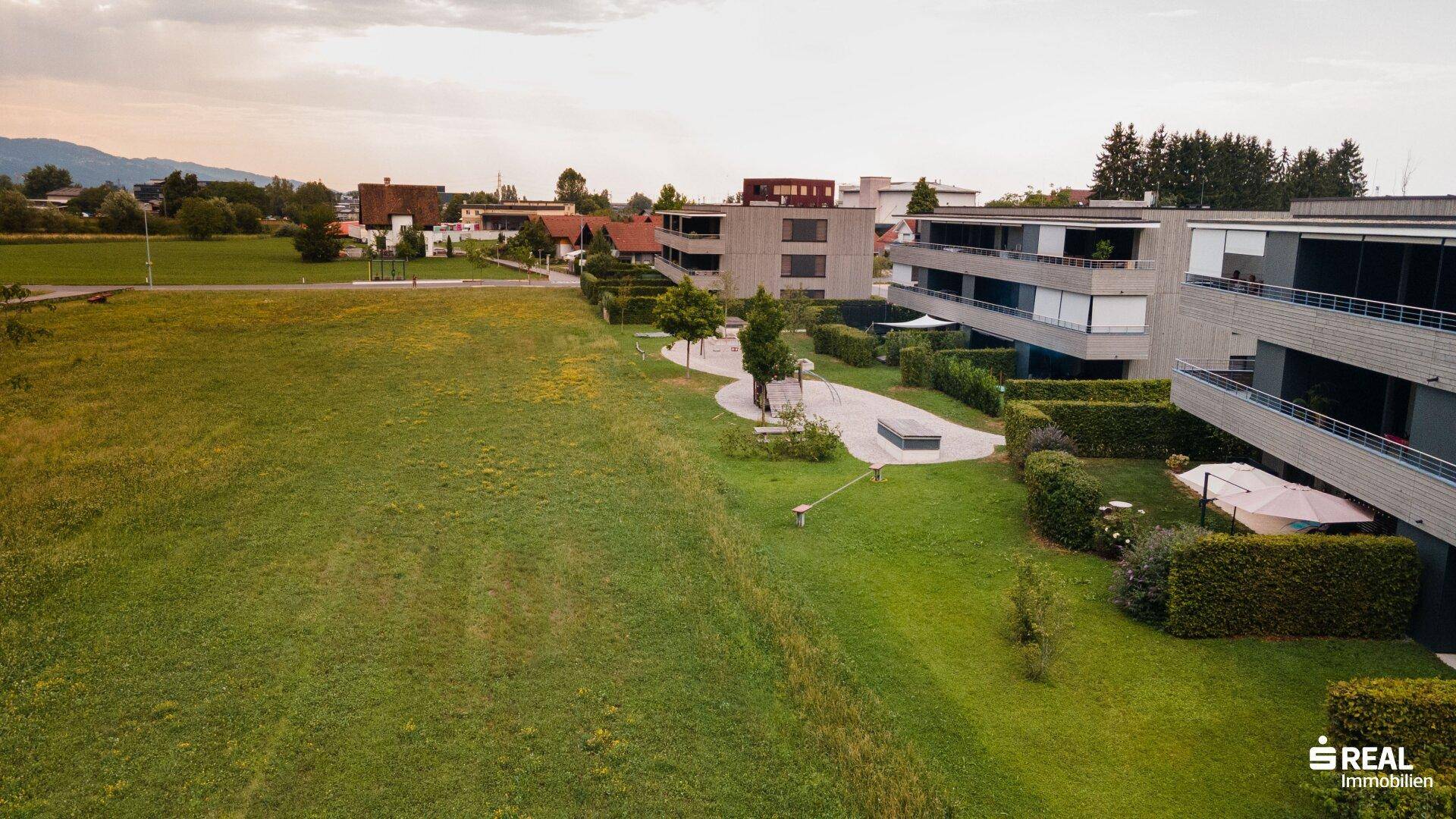 Luftaufnahme einer Wohnsiedlung mit modernen Gebäuden und weitläufigen Grünflächen.