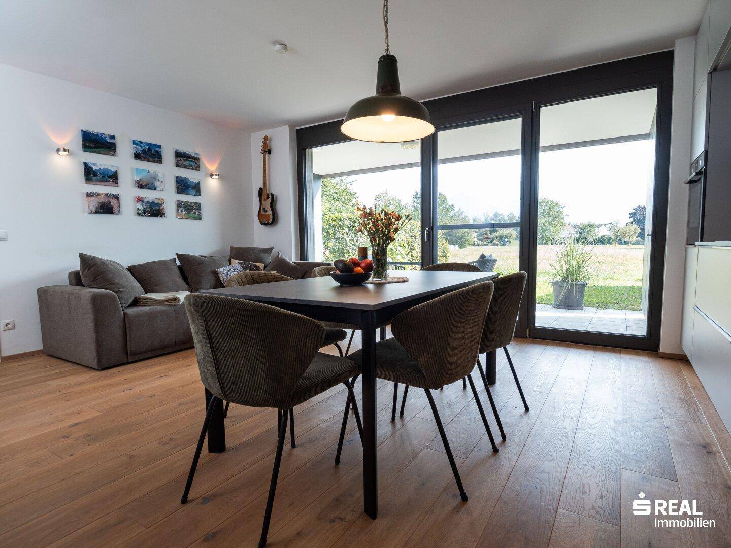 Heller Wohn-Essbereich mit Holzboden, Sofa und Zugang zur Terrasse.