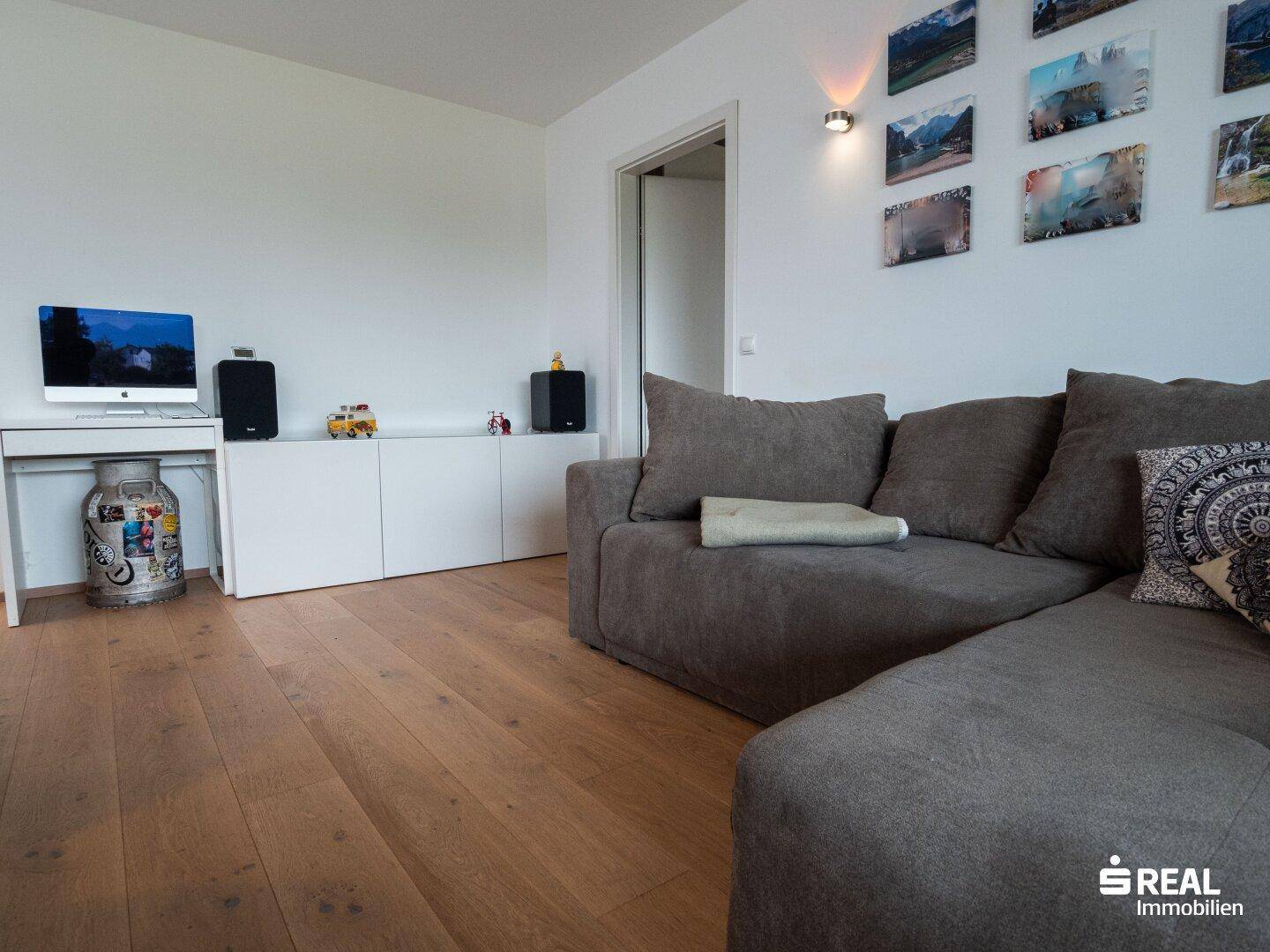 Gemütliches Wohnzimmer mit großem Sofa, Holzboden und modernen Dekorationen.