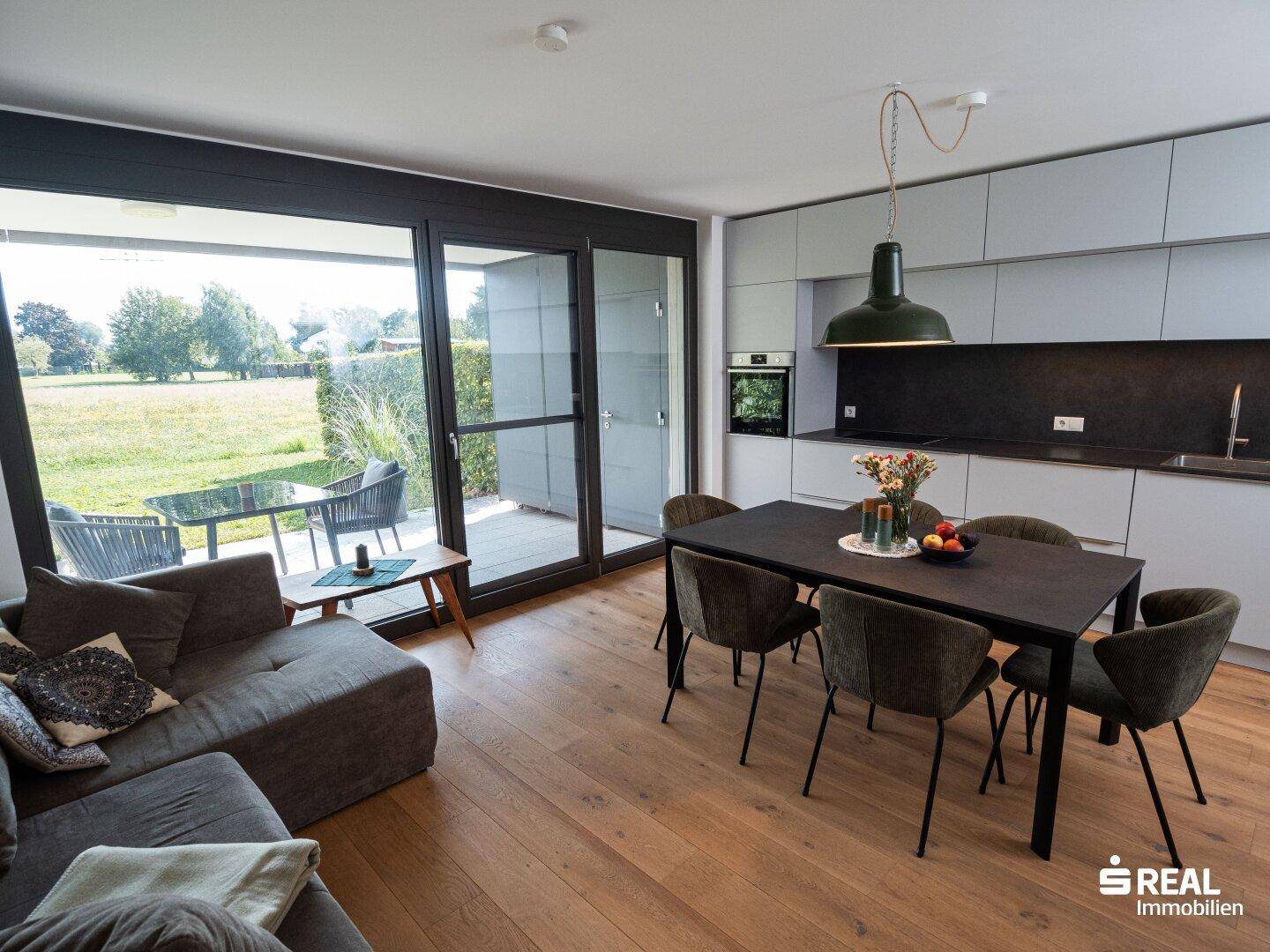 Geräumiger Wohn-Essbereich mit offener Küche, Holzboden und Zugang zur Terrasse.