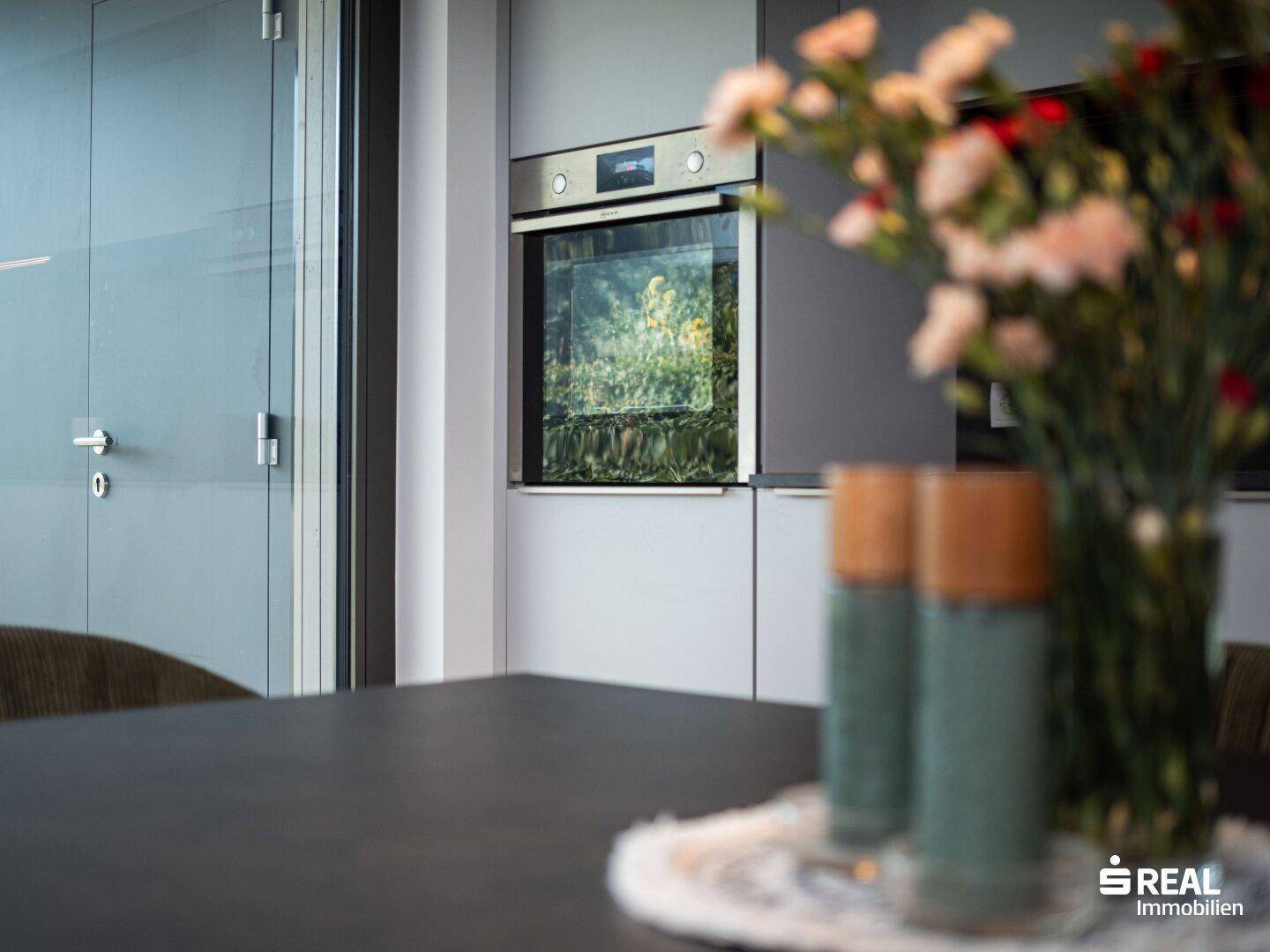 Detailansicht des Backofens in der modernen Küche mit Blumen auf dem Esstisch.