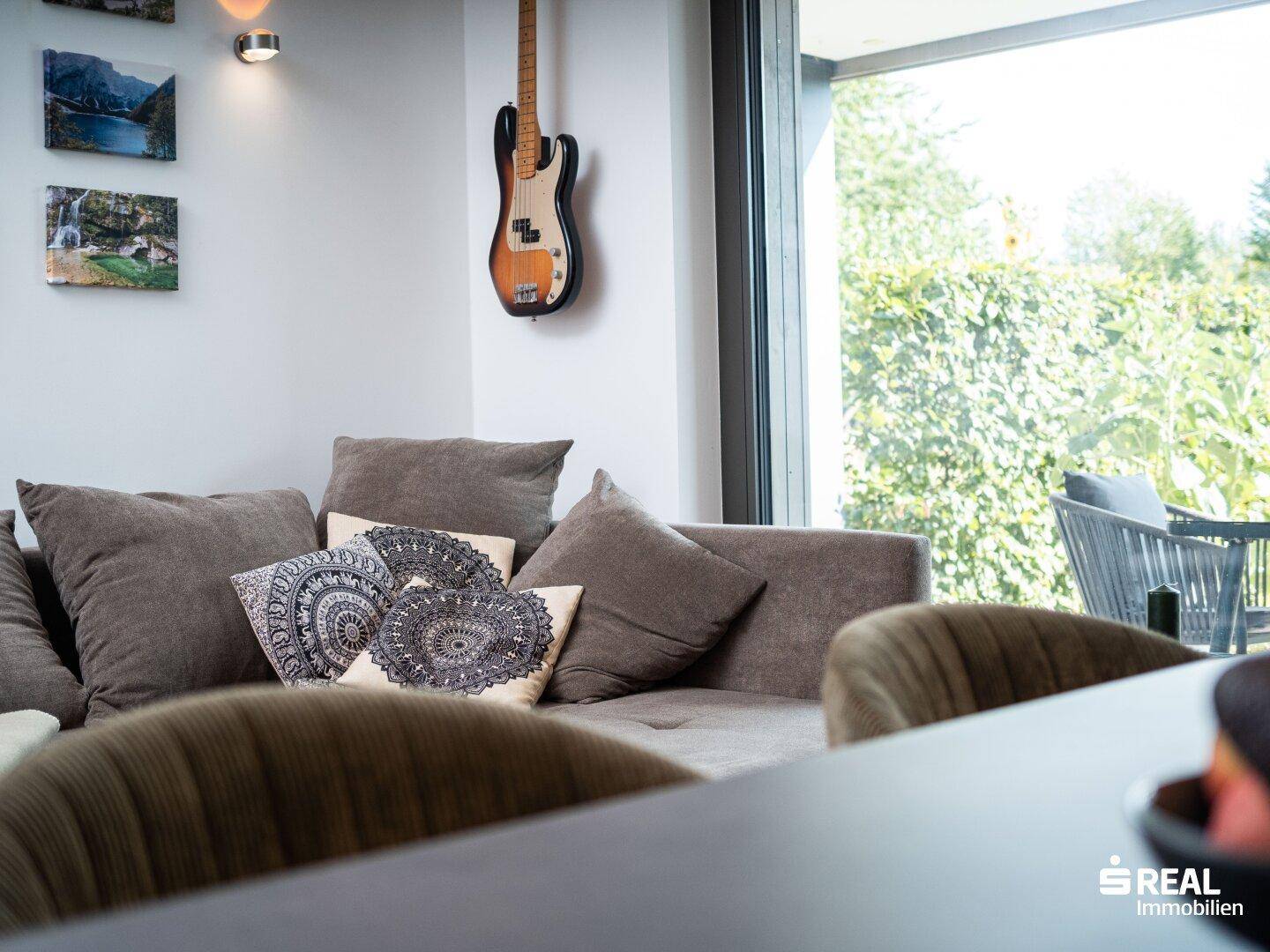 Gemütliche Sitzecke im Wohnzimmer mit Sofa und Blick ins Grüne.