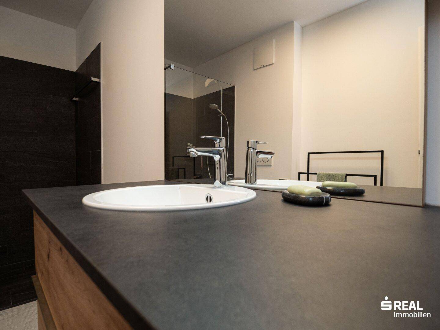Nahaufnahme des Waschbeckens und der dunklen Arbeitsplatte im modernen Badezimmer.