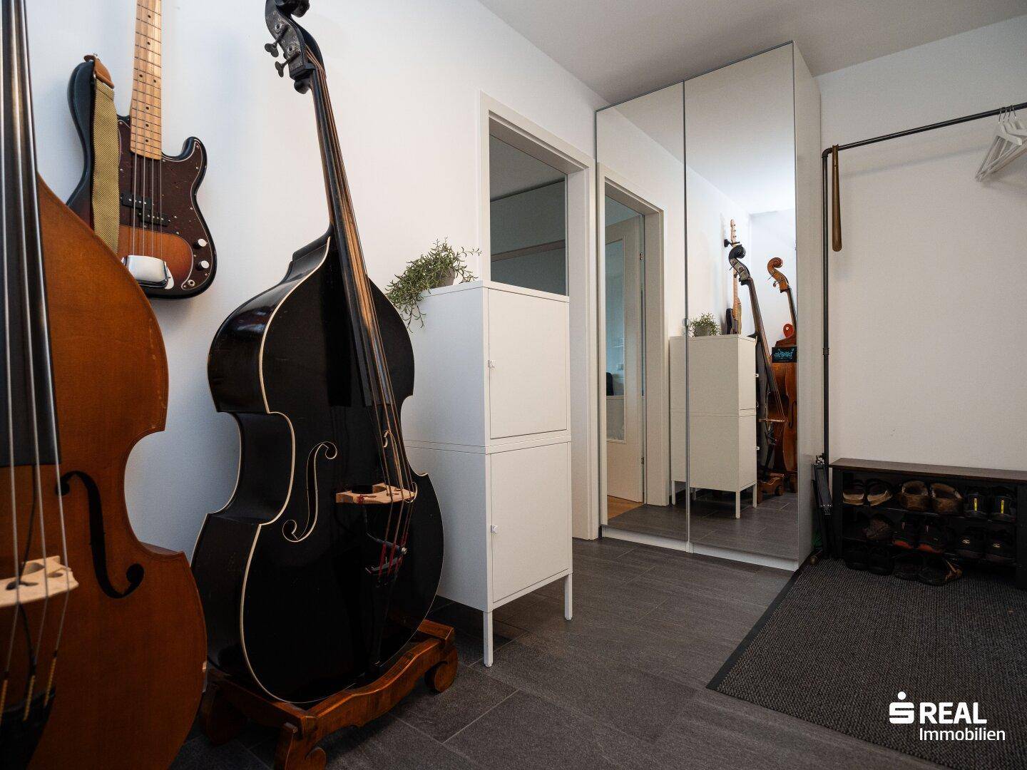 Eingangsbereich mit Spiegelschränken, Garderobe und Musikinstrumenten.