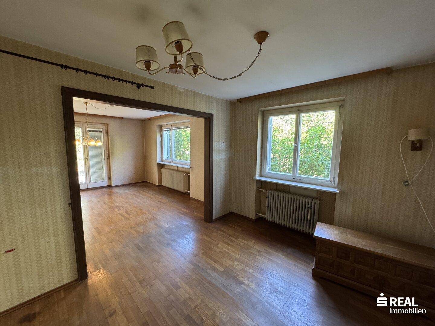 Zwei miteinander verbundene Zimmer mit Parkettboden und Fenstern, die viel Licht hereinlassen.