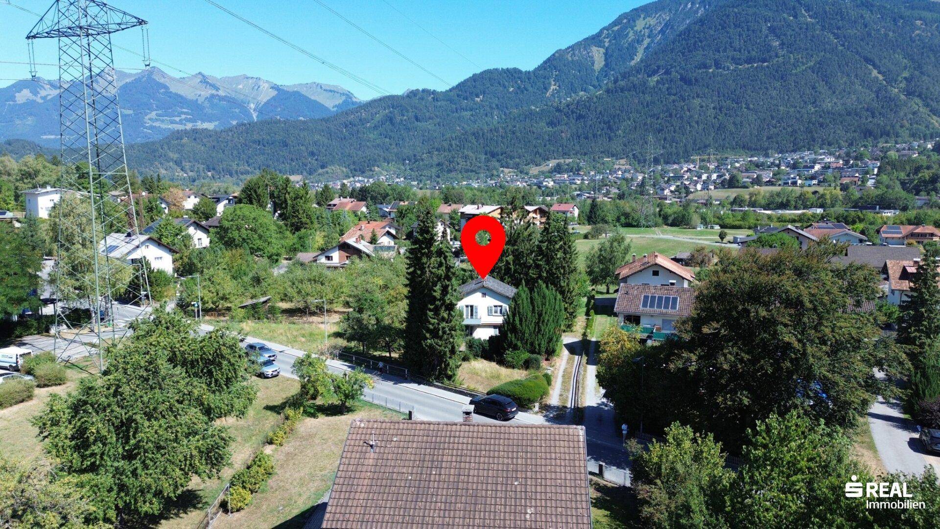 Luftaufnahme der Immobilie mit Standortmarkierung, umgeben von Natur und Bergen.