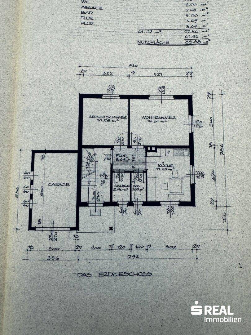 Grundriss des Erdgeschosses mit Wohnzimmer, Küche, Arbeitszimmer, WC und integrierter Garage.