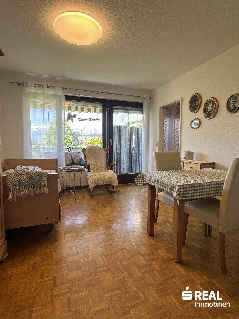 Heller Wohn-Essbereich mit traditionellem Parkettboden und direktem Zugang zum Balkon.