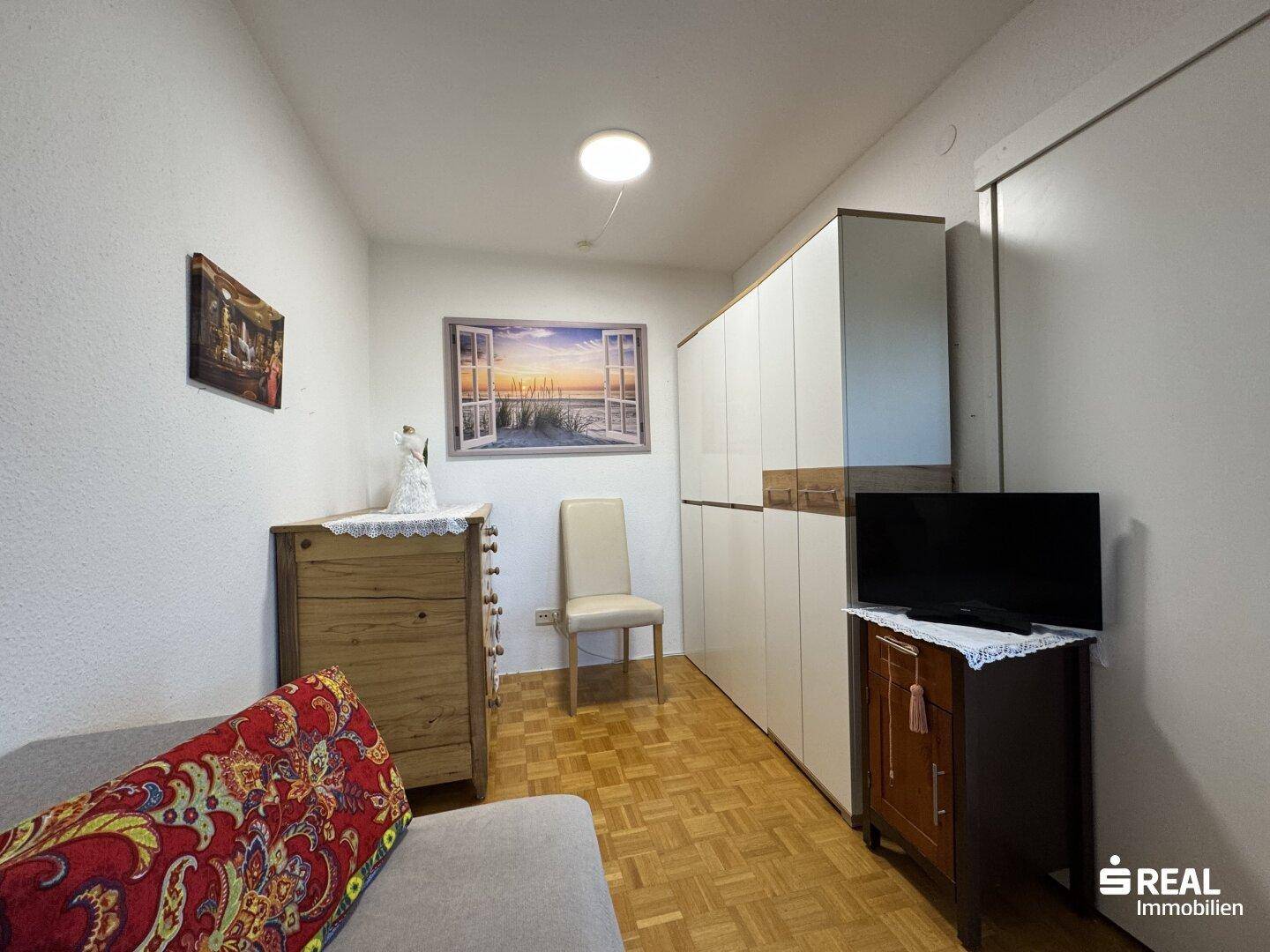 Helles Schlafzimmer mit Parkettboden und viel Stauraum durch den großen Kleiderschrank.