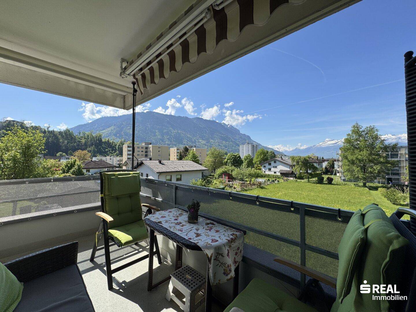 Sonniger Balkon mit Sitzgelegenheiten und weitem Blick auf die umliegende Bergwelt.