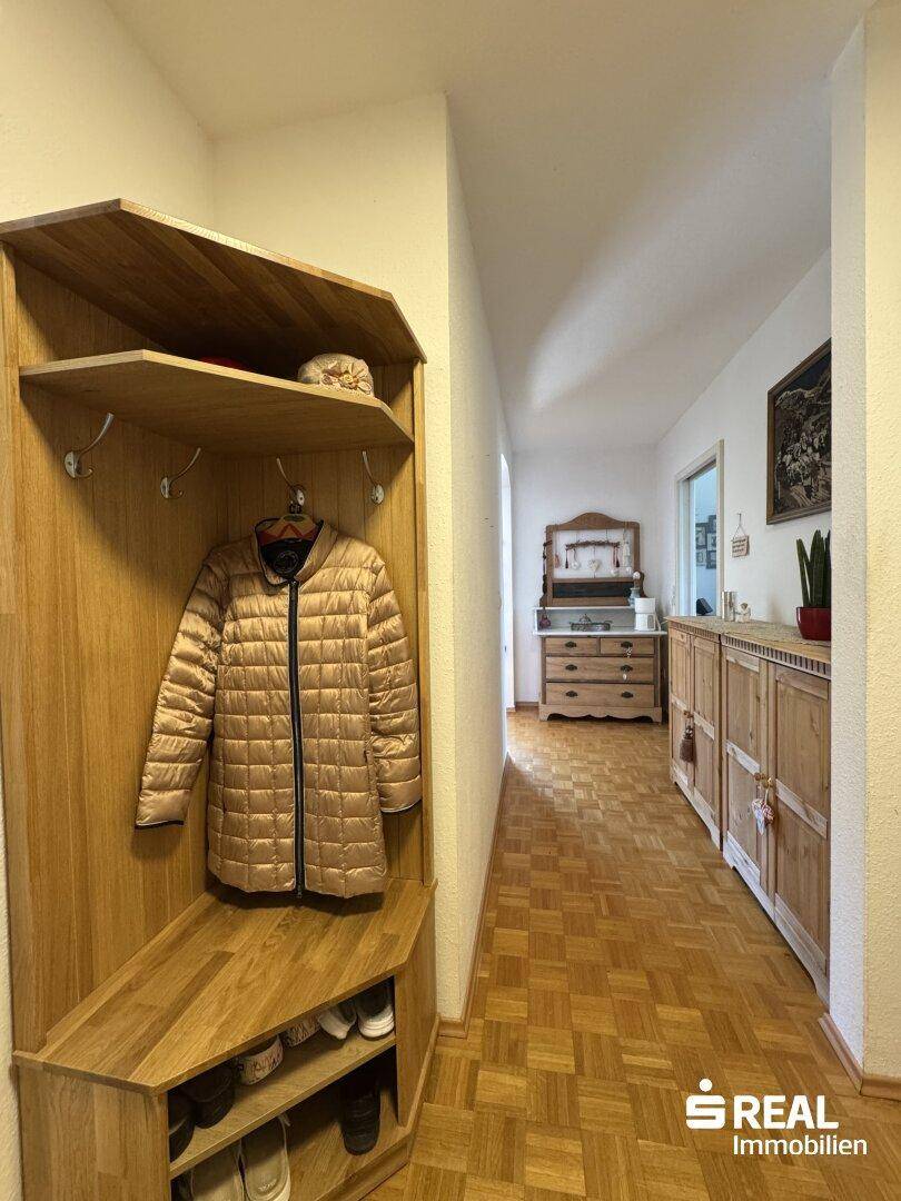 Heller Flur mit praktischer Garderobe und integrierten Holzschränken für Stauraum.