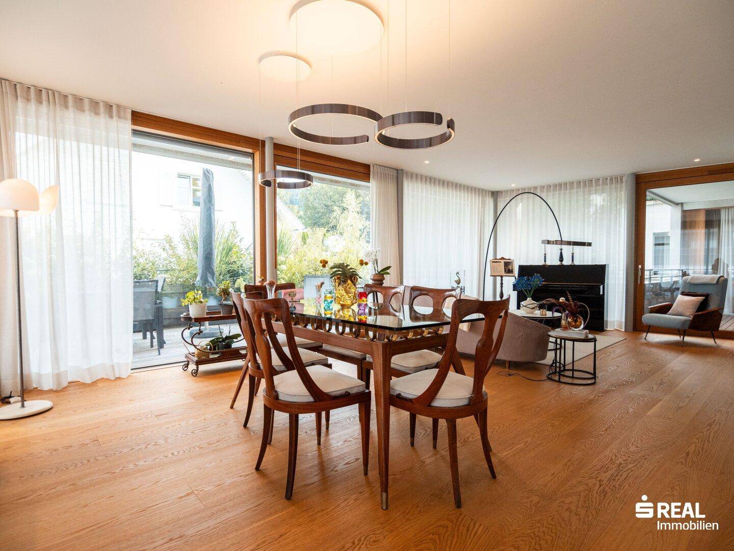 Heller Wohn- und Essbereich mit Holzboden, großzügigen Fenstern und Zugang zur Terrasse.