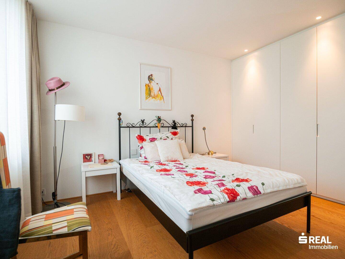 Helles Schlafzimmer mit Einzelbett, floraler Bettwäsche und praktischen Einbauschränken, modern eingerichtet.