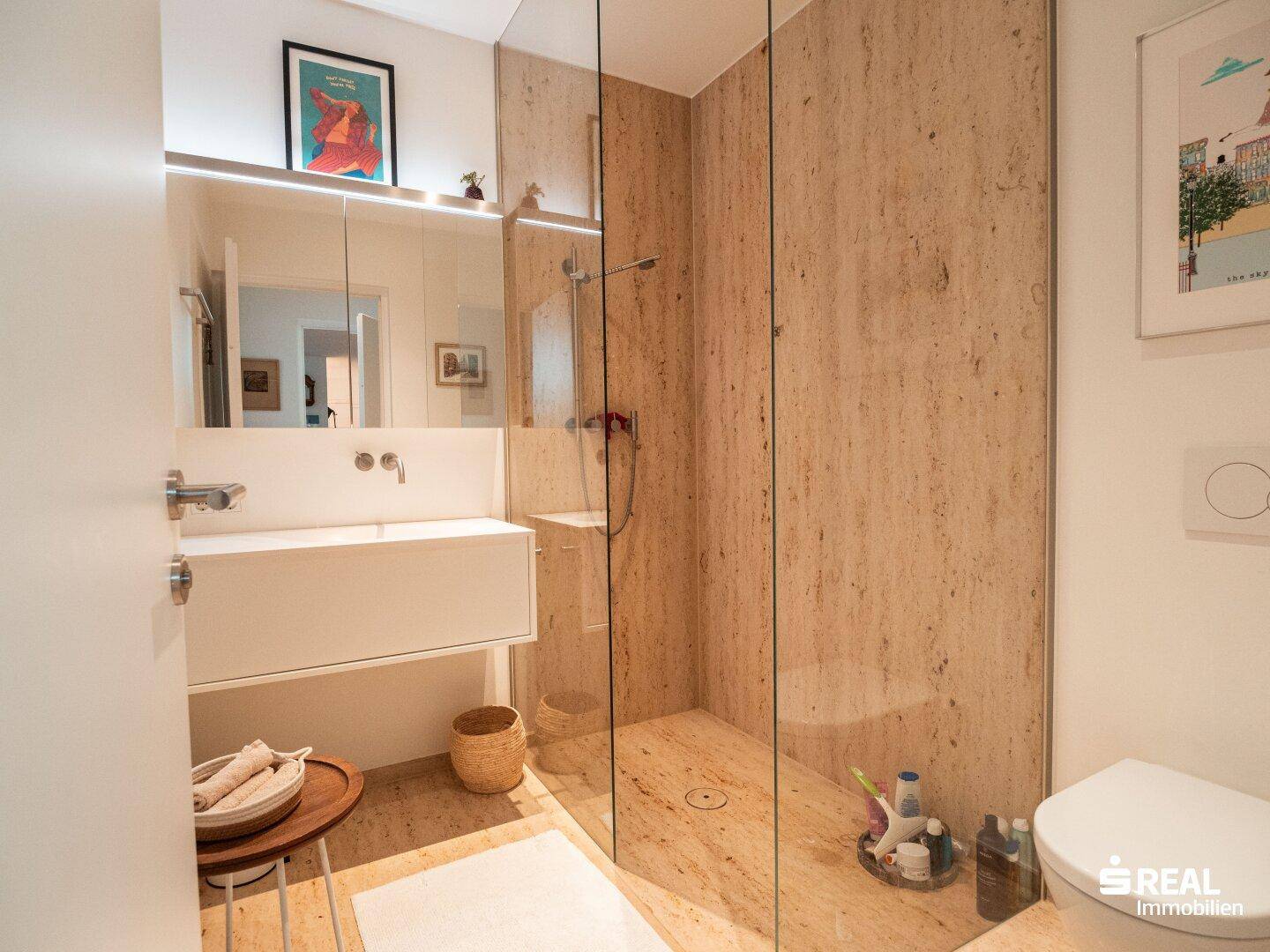 Zeitgemäßes Badezimmer mit schwebendem Waschtisch, begehbarer Dusche und WC, alles in hellen Naturtönen gehalten.