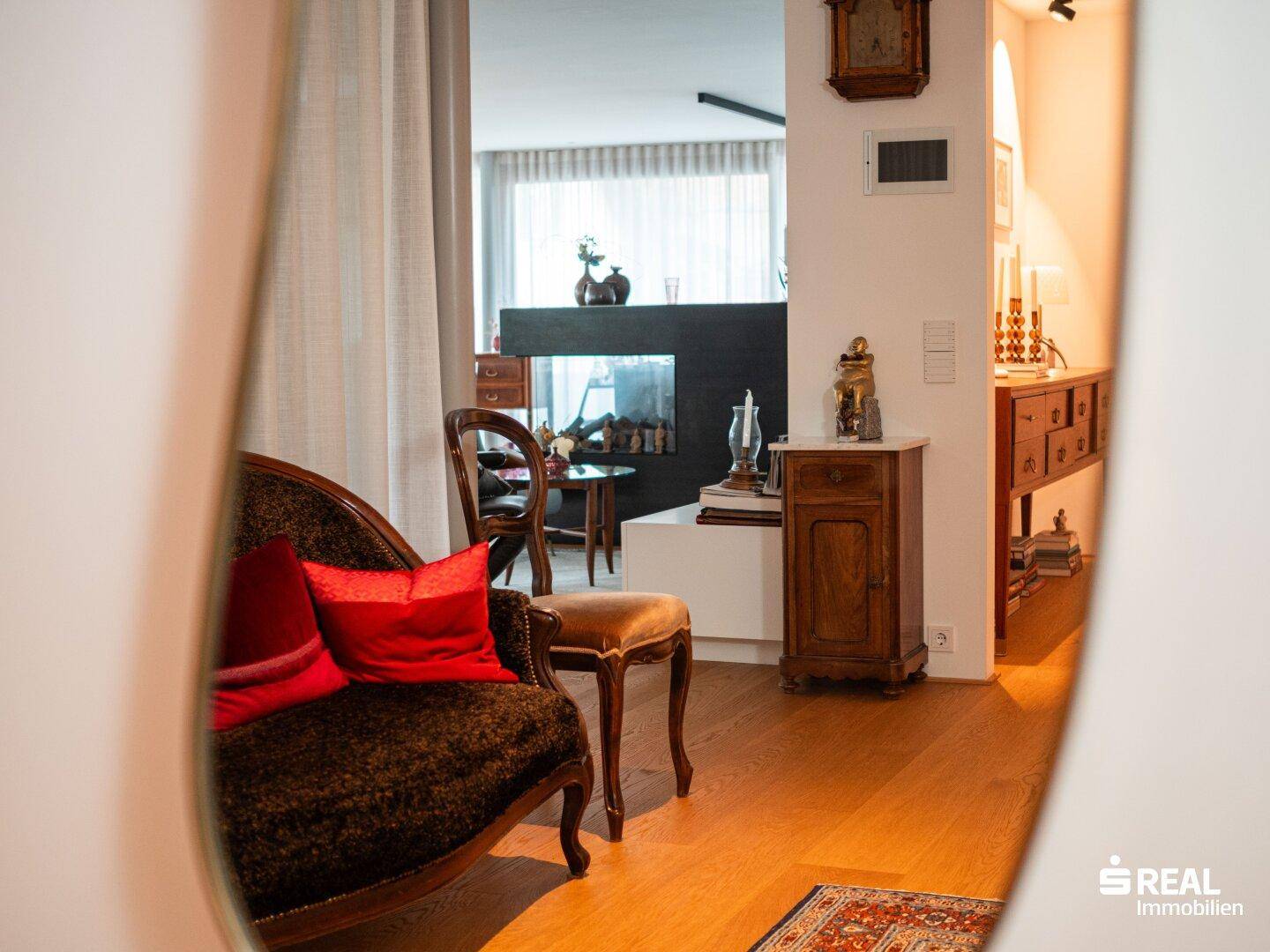 Spiegelung des Wohnbereichs mit elegantem Sofa, Kamin und Holzboden, der eine gemütliche Atmosphäre schafft.