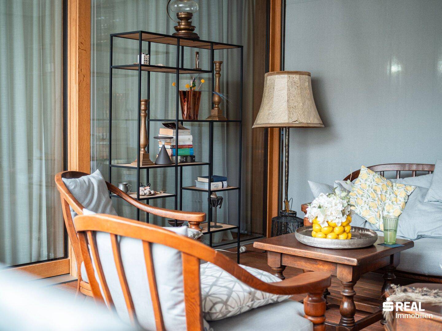 Gemütlicher Balkon mit Holzboden, bequemen Sitzmöbeln und einem Bücherregal.