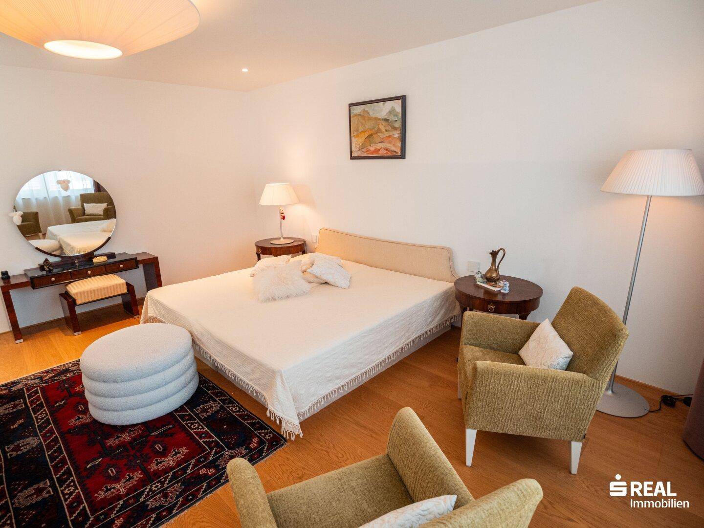 Helles Schlafzimmer mit Doppelbett, Holzboden und einem Schminktisch.