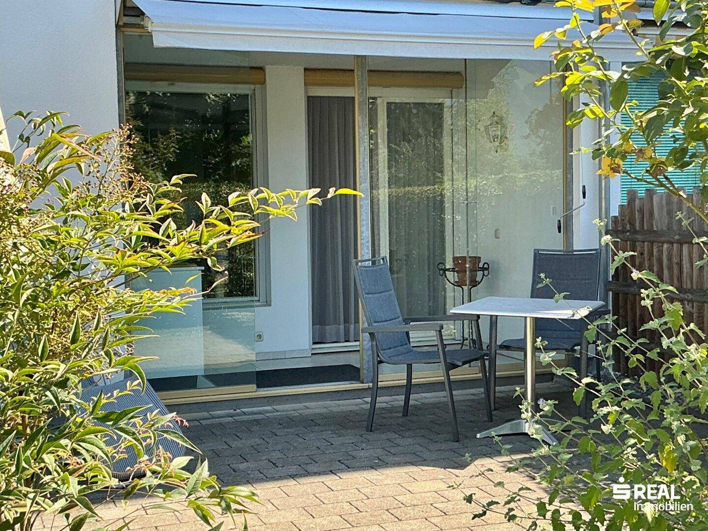 Gemütliche Terrasse mit Sitzgelegenheiten und Markise, direkt am Gebäude gelegen.