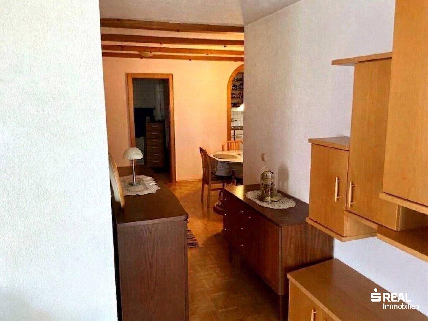 Übergangsbereich vom Wohnzimmer zum Essbereich mit Holzbalken und traditionellen Möbeln.