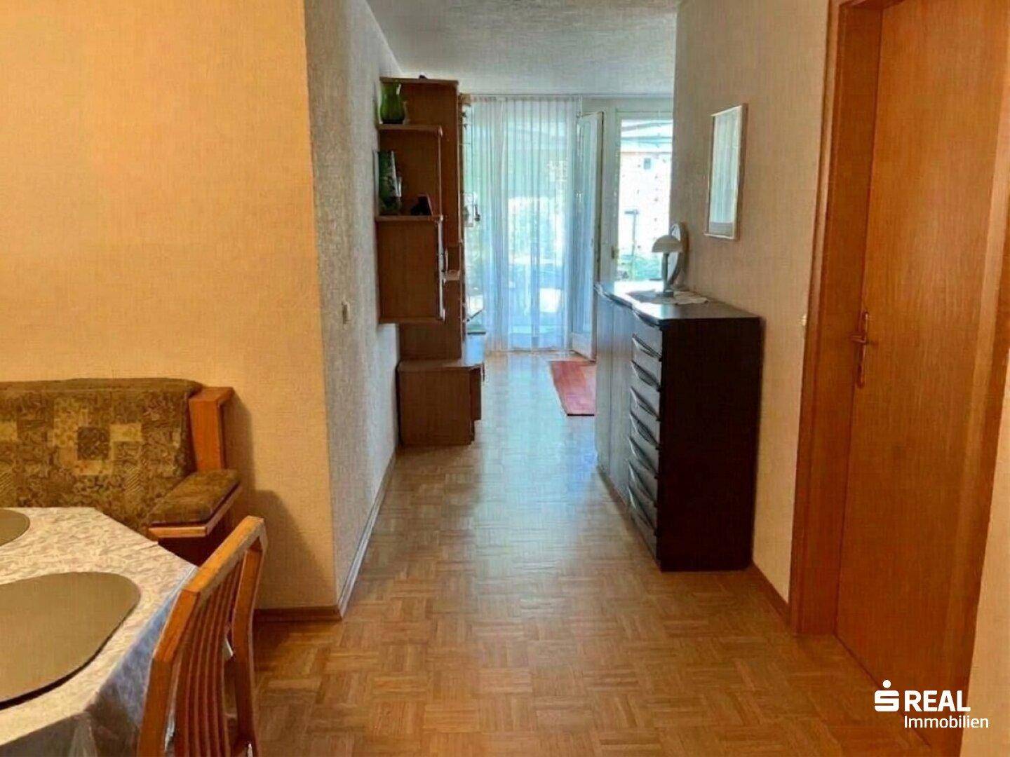 Heller Flur mit Laminatboden, der zu einem weiteren Wohnbereich führt.
