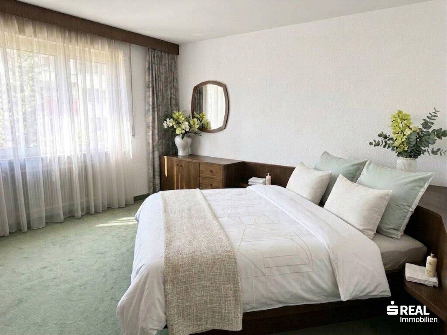 Geräumiges Schlafzimmer mit Doppelbett, grünem Teppichboden und viel Tageslicht.