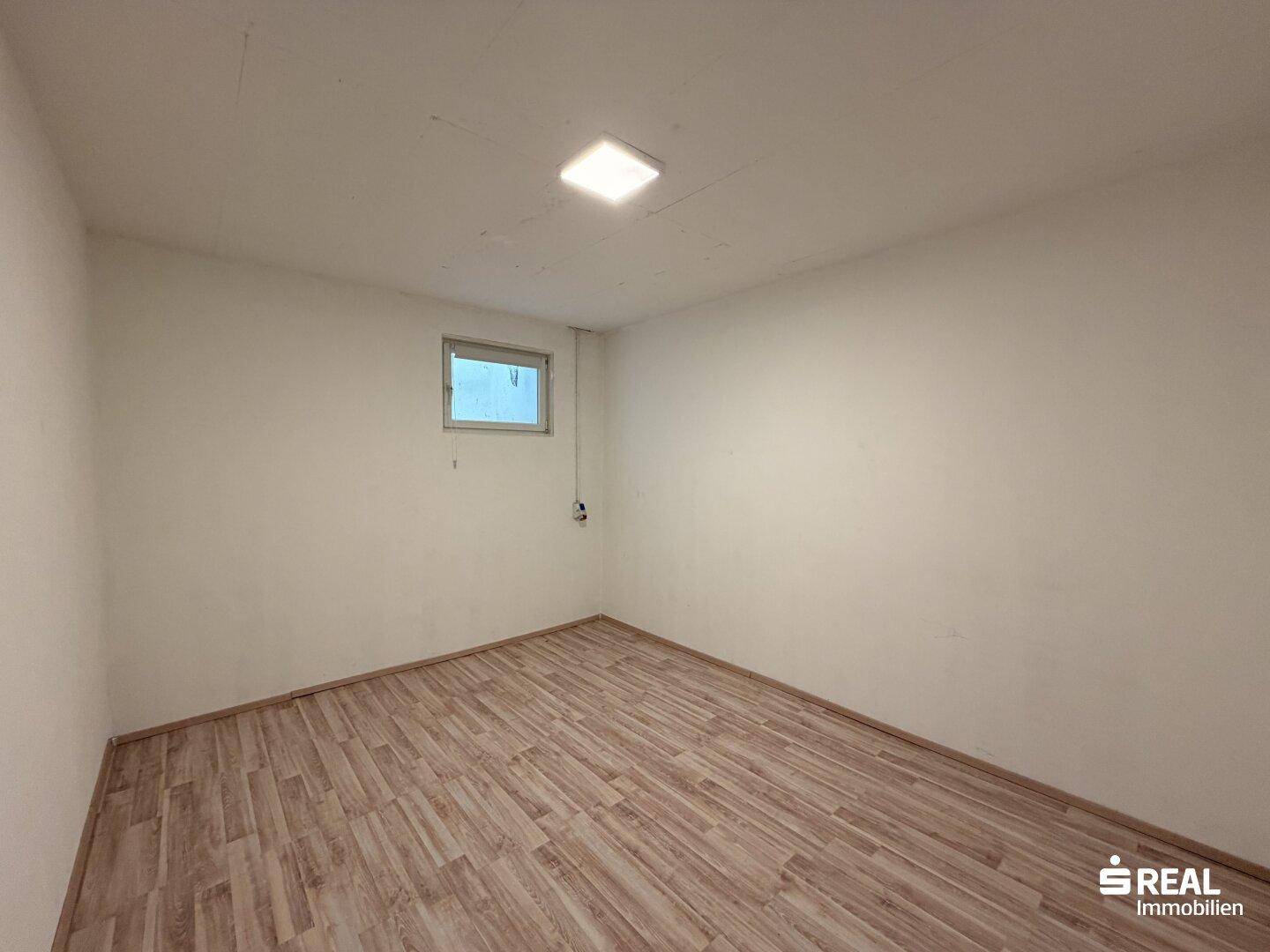 Einfacher Kellerraum mit Laminatboden und kleinem Fenster für Belüftung.
