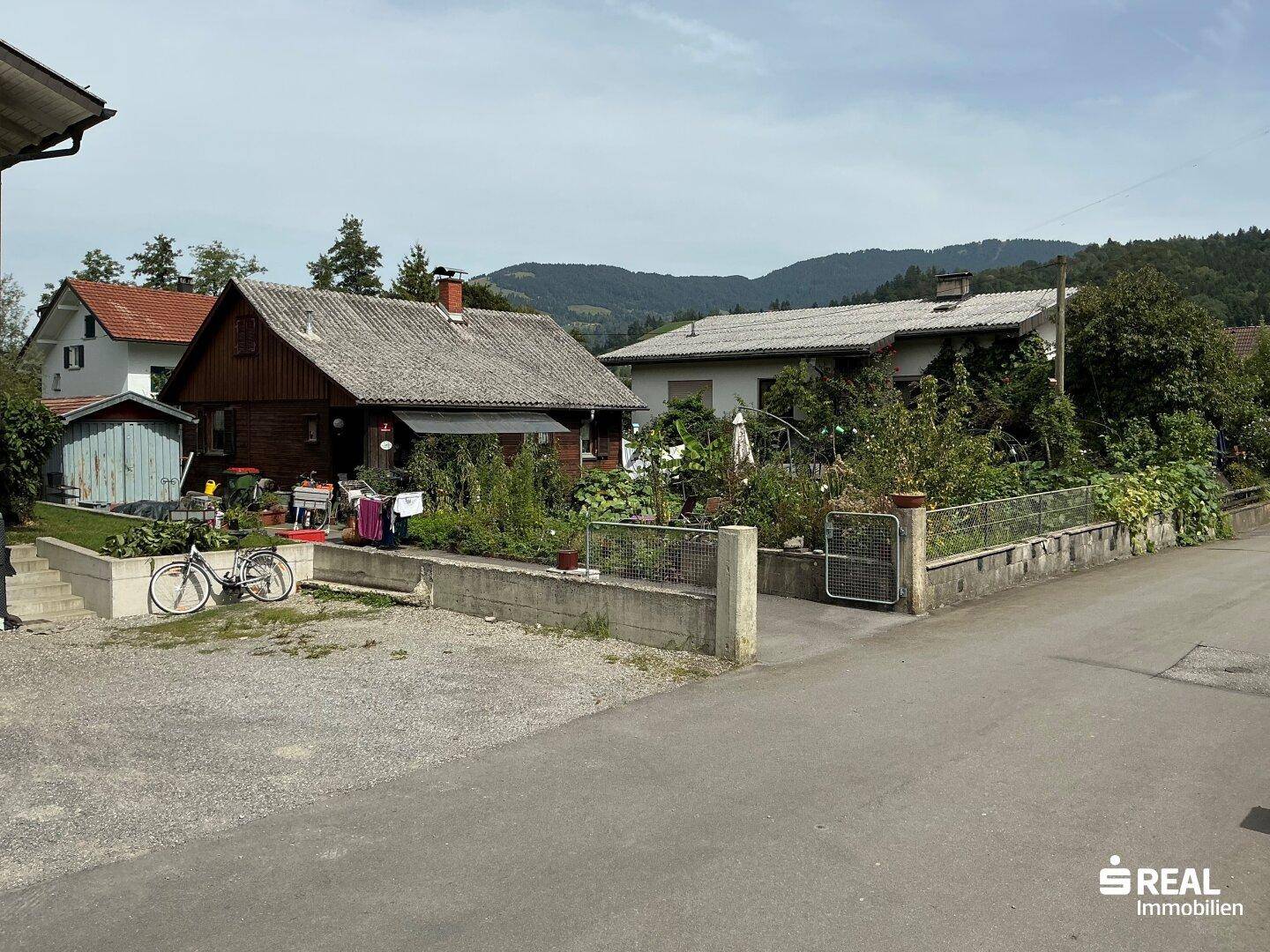 Gesamtansicht des Holzhauses mit Garten und Blick auf die umliegende ländliche Landschaft.