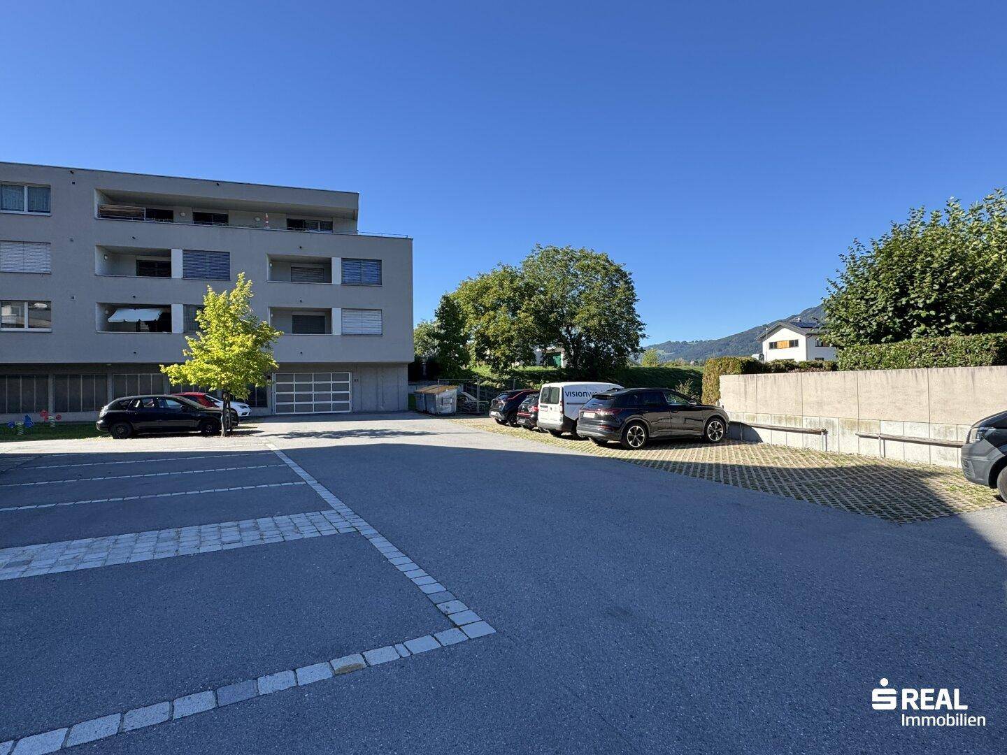 Außenansicht des Gebäudes mit großem Parkplatz und umliegender Grünfläche.