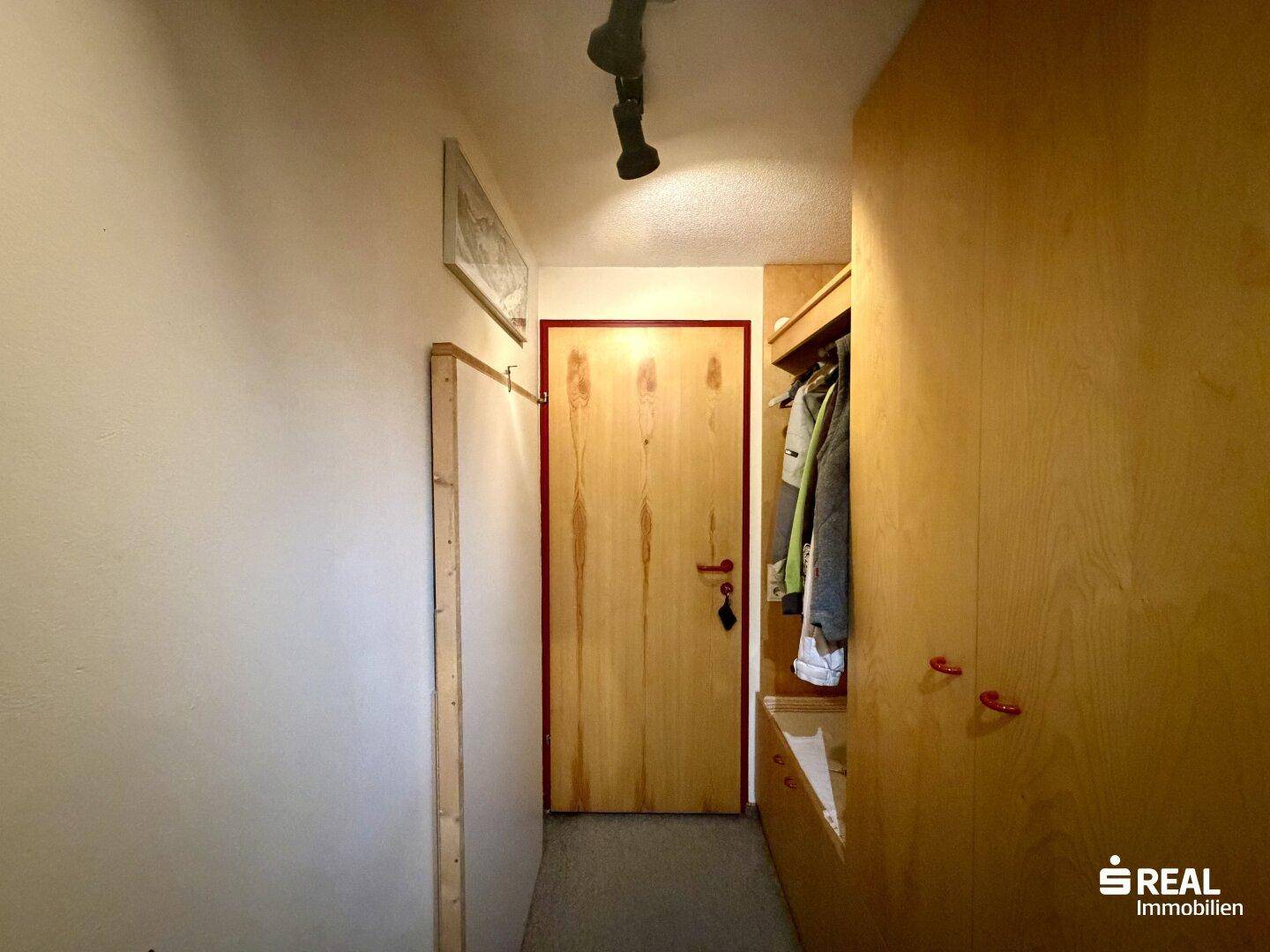 Heller Flur mit Einbauschränken und Holztür, der zu weiteren Räumen führt.