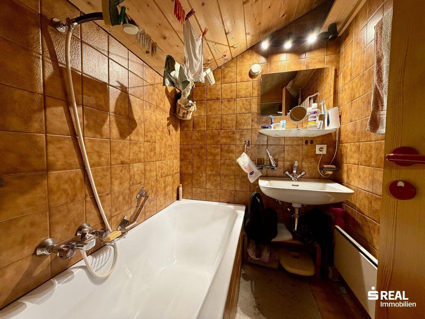 Badezimmer mit braunen Fliesen, Badewanne und Waschbecken im traditionellen Stil.