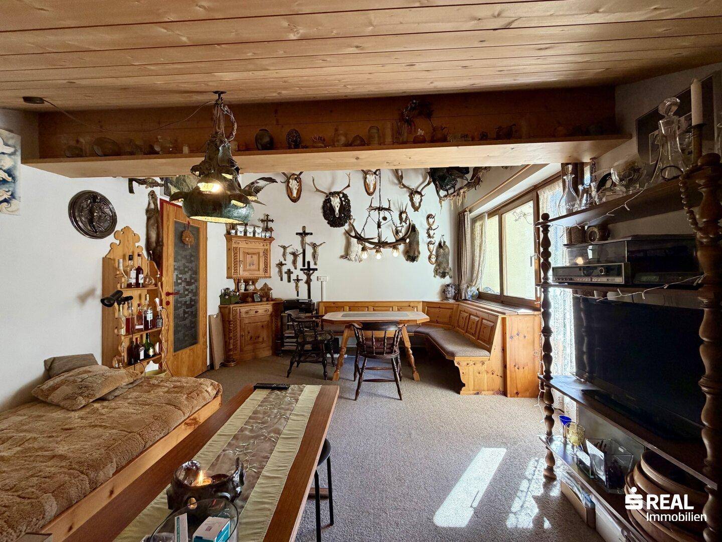 Geräumiger Wohnbereich mit Holzbalken, traditionellen Sitzgelegenheiten und alpiner Dekoration.