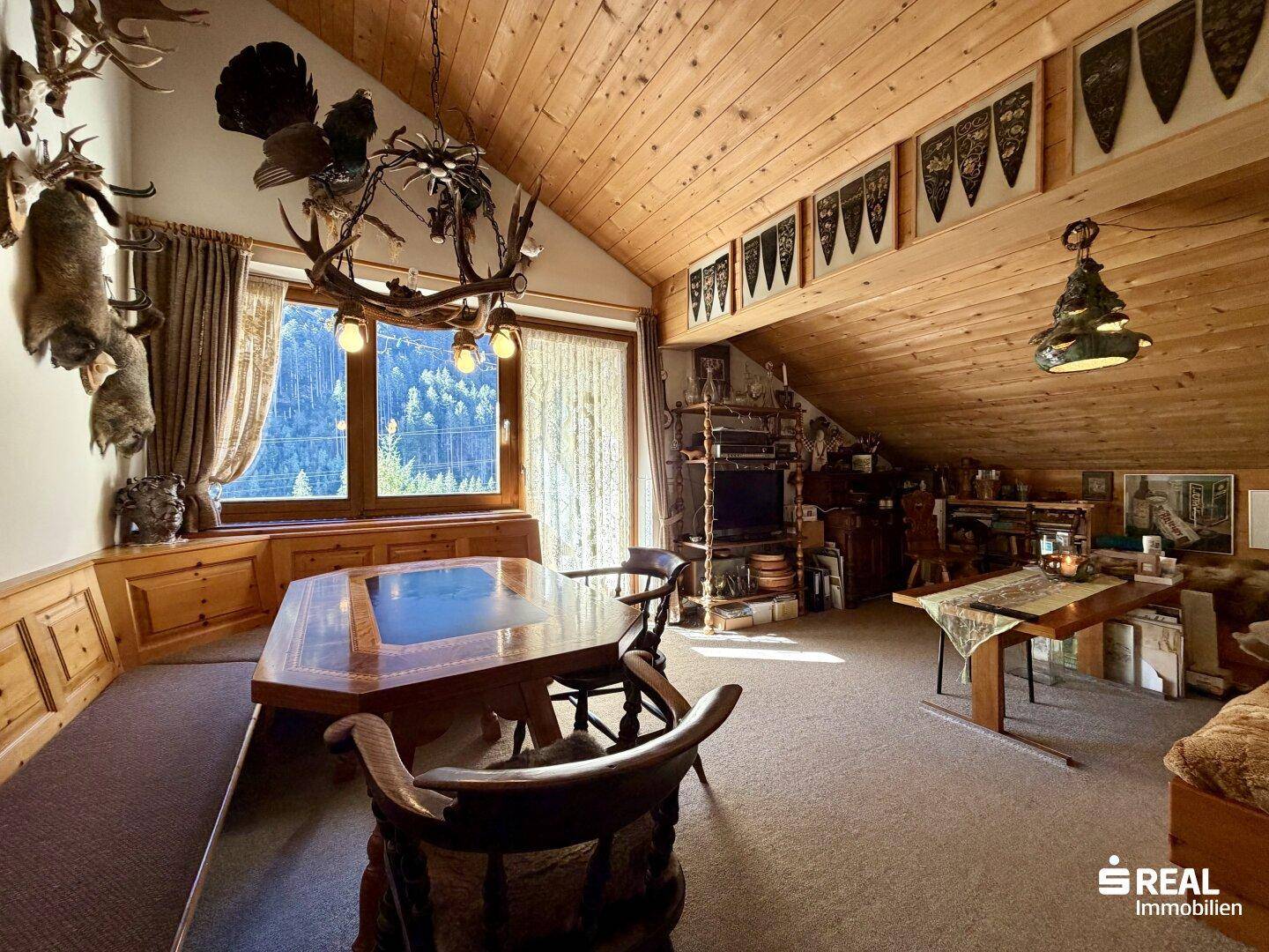 Rustikales Wohnzimmer im alpinen Stil mit Holztäfelung, Esstisch und traditioneller Jagddekoration.