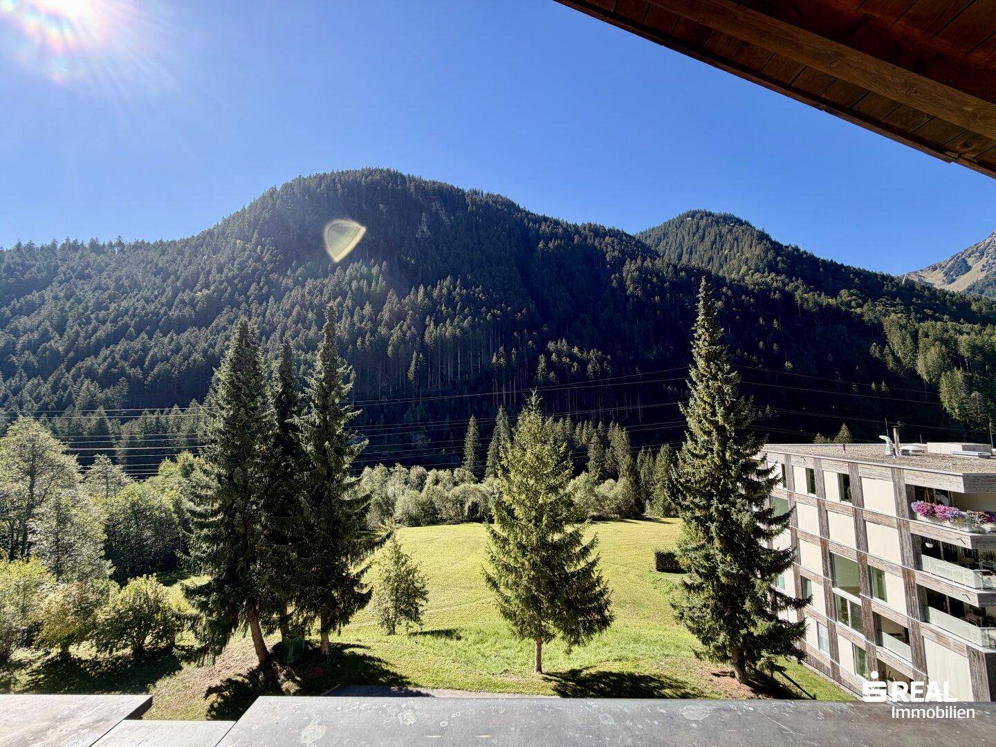 Sonniger Balkon mit weitem Blick auf grüne Wiesen und die umliegende Berglandschaft.